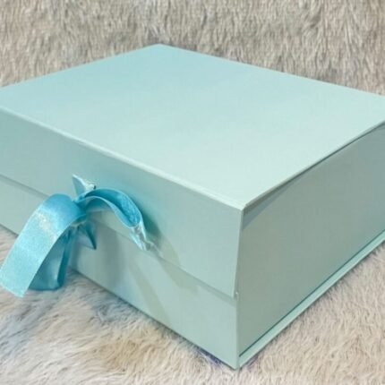 Elegant light blue ribbon hamper box—ideal for upscale corporate gifting—rests on a beige fabric surface.