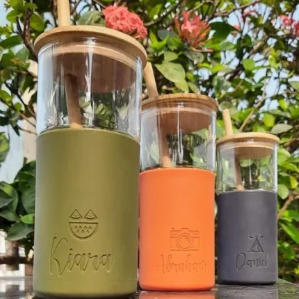 Personalized smoothie tumblers with bamboo lids, perfect for corporate gifts, arranged outdoors among flowers.