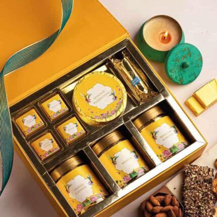 Corporate gift box with snacks, chocolates, floral labels, hummingbird motif, candle and nuts.